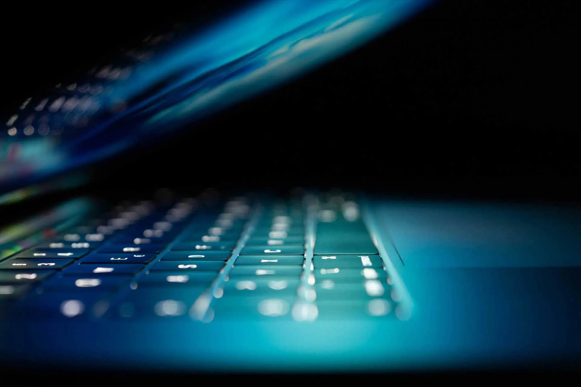 partially closed laptop keyboard dark background