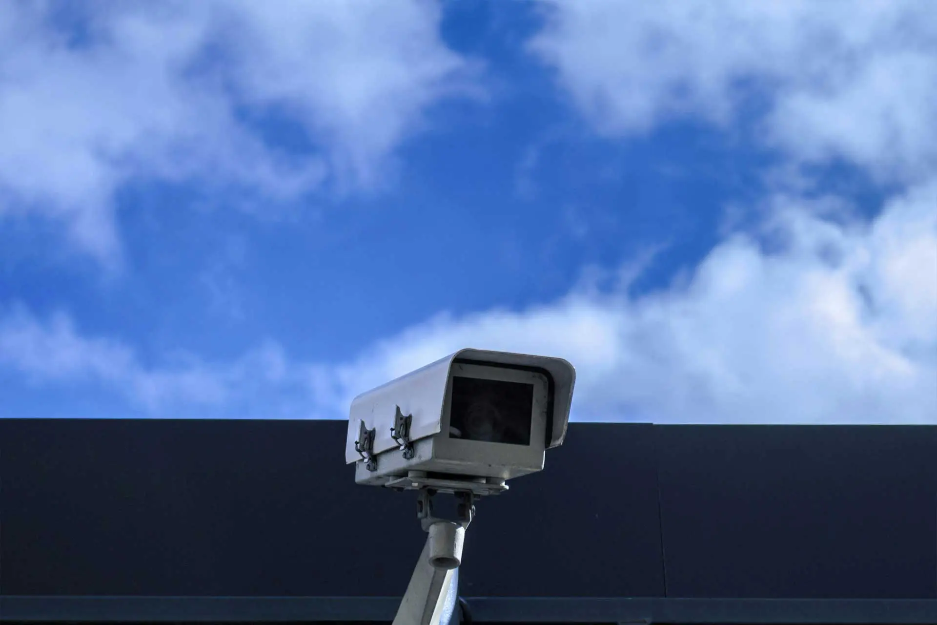 security camera on building rooftop blue sky background